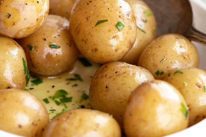 salt potatoes in bowl with melted butter and herbs