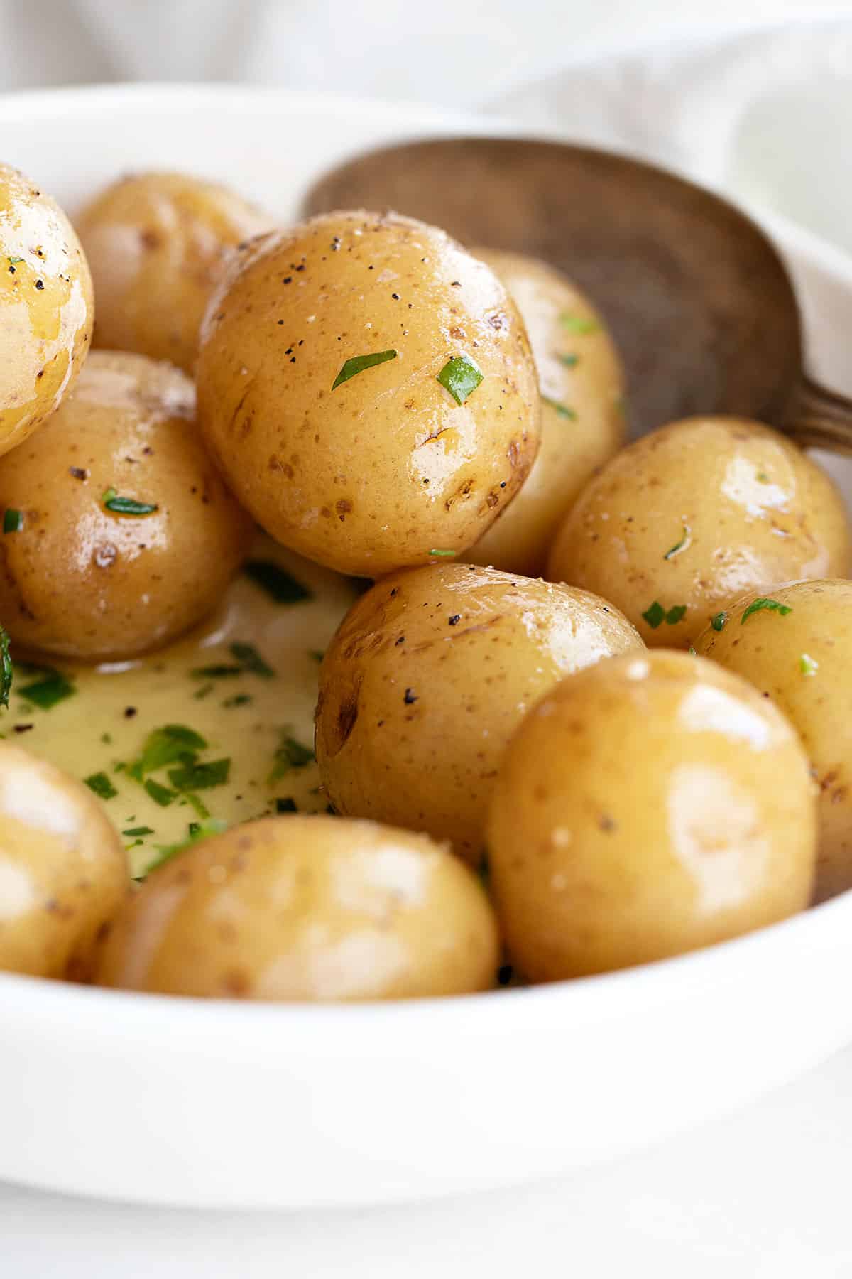 salt potatoes in bowl with melted butter and herbs