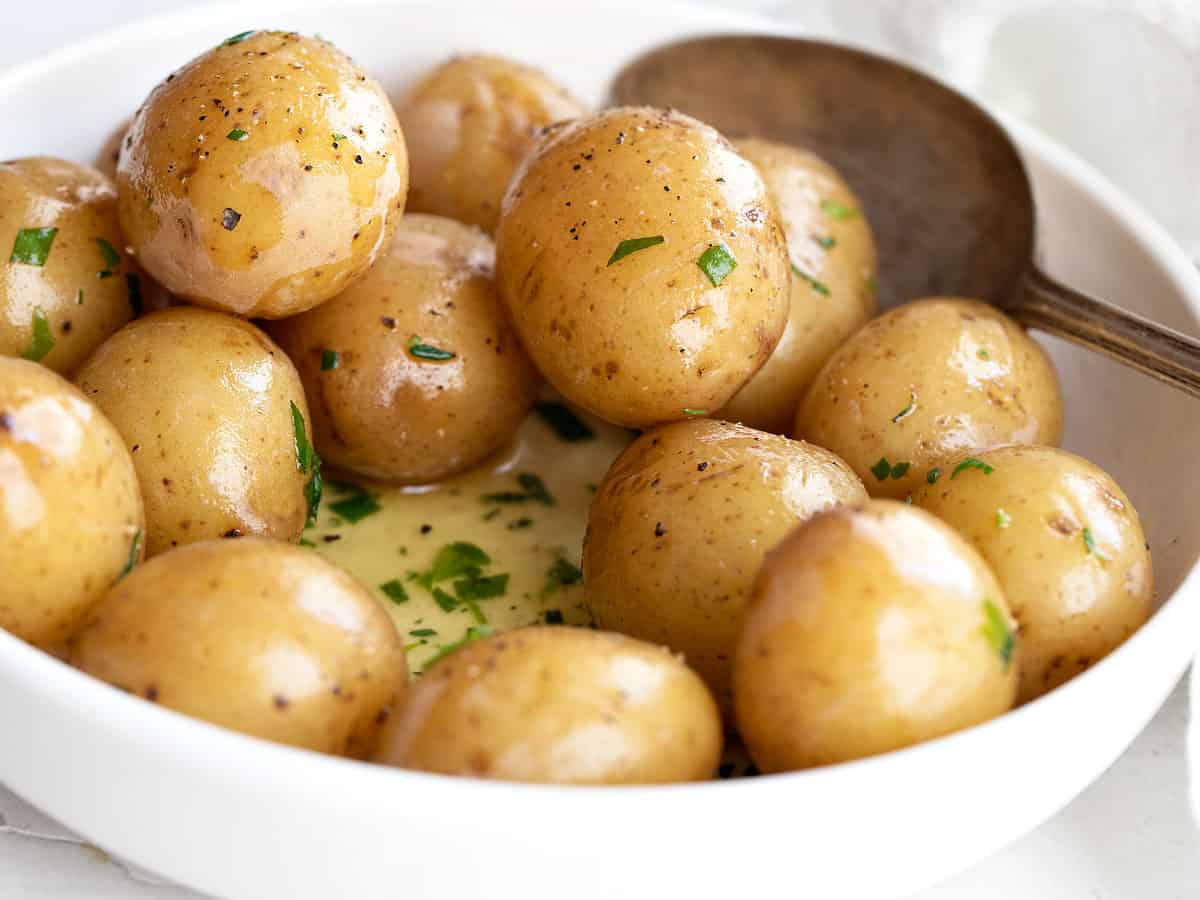 salt potatoes in bowl with melted butter and herbs