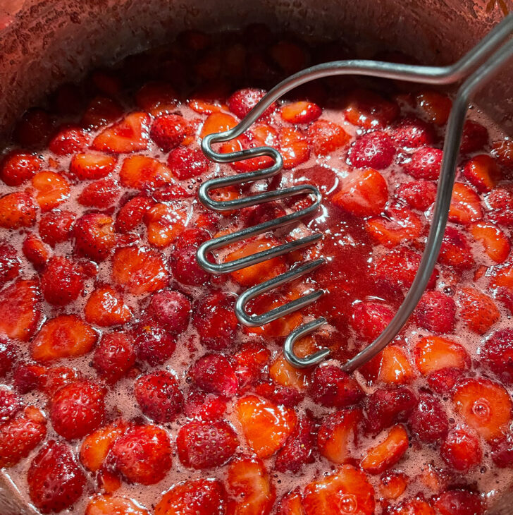 Mashing the strawberries in the pot.
