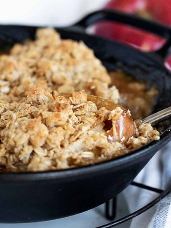baked apples topped with oat crumble in cast iron skillet