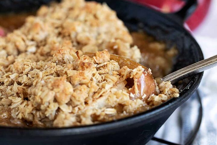 baked apples topped with oat crumble in cast iron skillet