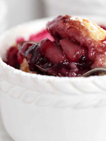 Blackberry pear cobbler in ramekin with spoon.