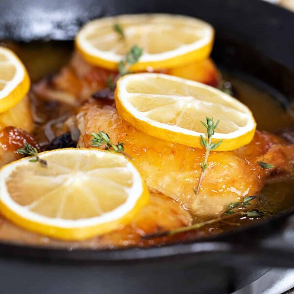 glazed lemon chicken thighs in pan with lemon slices