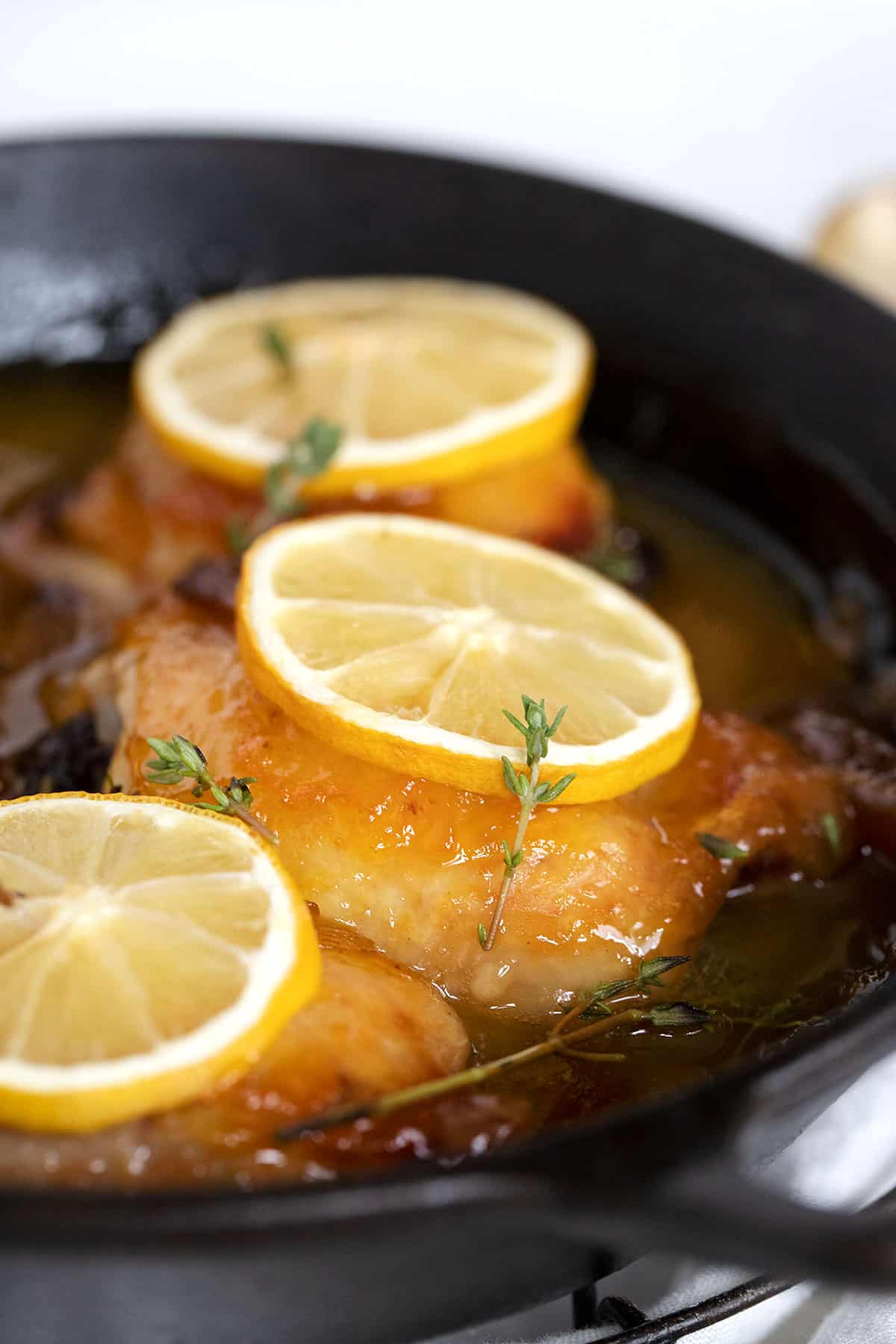 glazed lemon chicken thighs in pan with lemon slices
