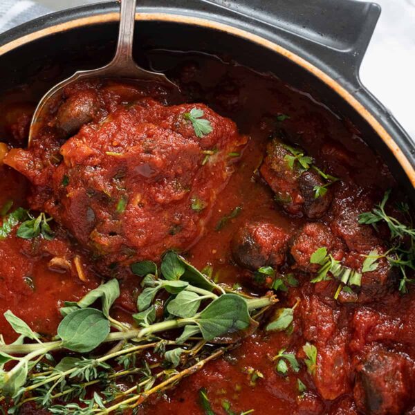 chicken cacciatore in pan with spoon and herbs