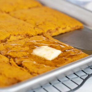 sheet-pan pumpkin pancakes in pan with maple syrup and butter