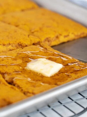 sheet-pan pumpkin pancakes in pan with maple syrup and butter