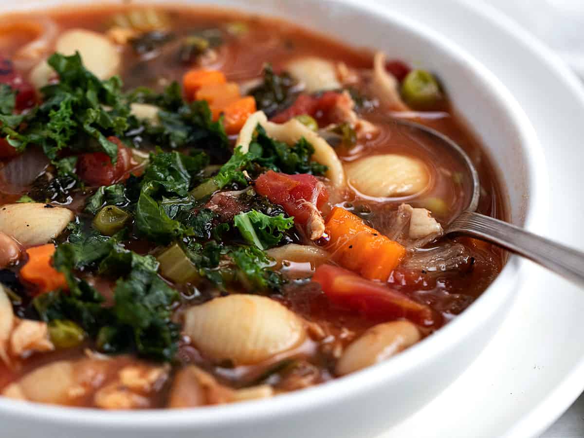 turkey vegetable soup in white bowl with spoon