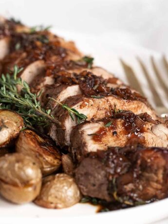 fig balsamic pork tenderloin sliced on platter with roasted potatoes