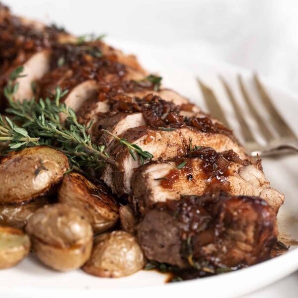 fig balsamic pork tenderloin sliced on platter with roasted potatoes