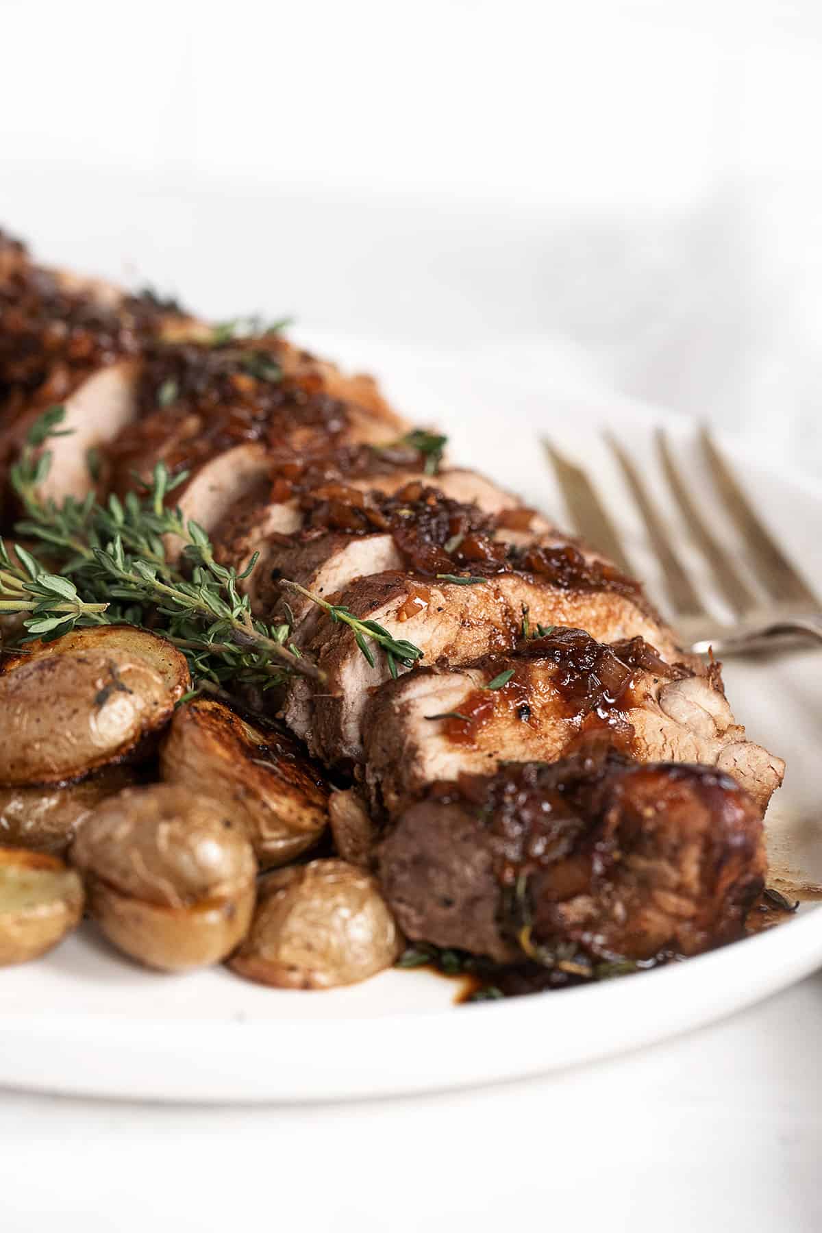 fig balsamic pork tenderloin sliced on platter with roasted potatoes