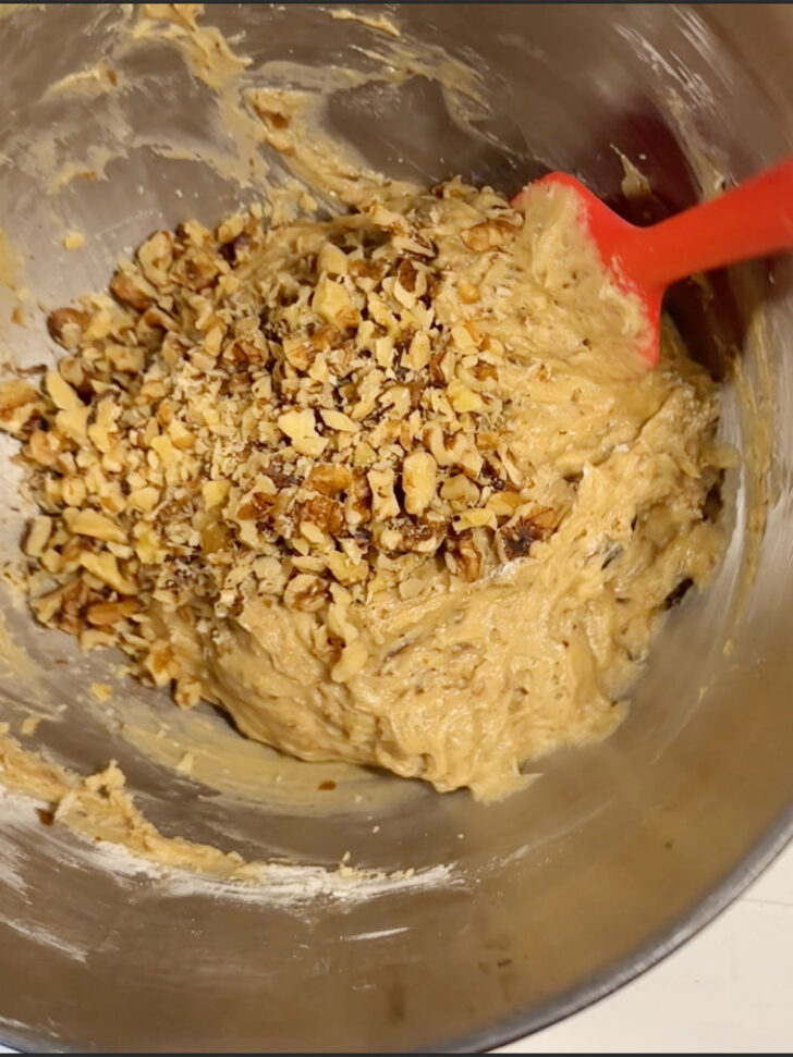 Folding chopped nuts into the batter.