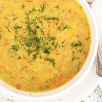 Polish potato and dill pickle soup in white bowl with spoon