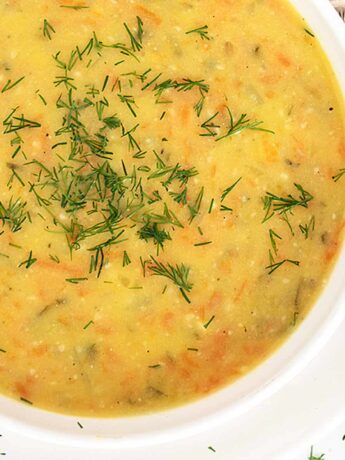 Polish potato and dill pickle soup in white bowl with spoon