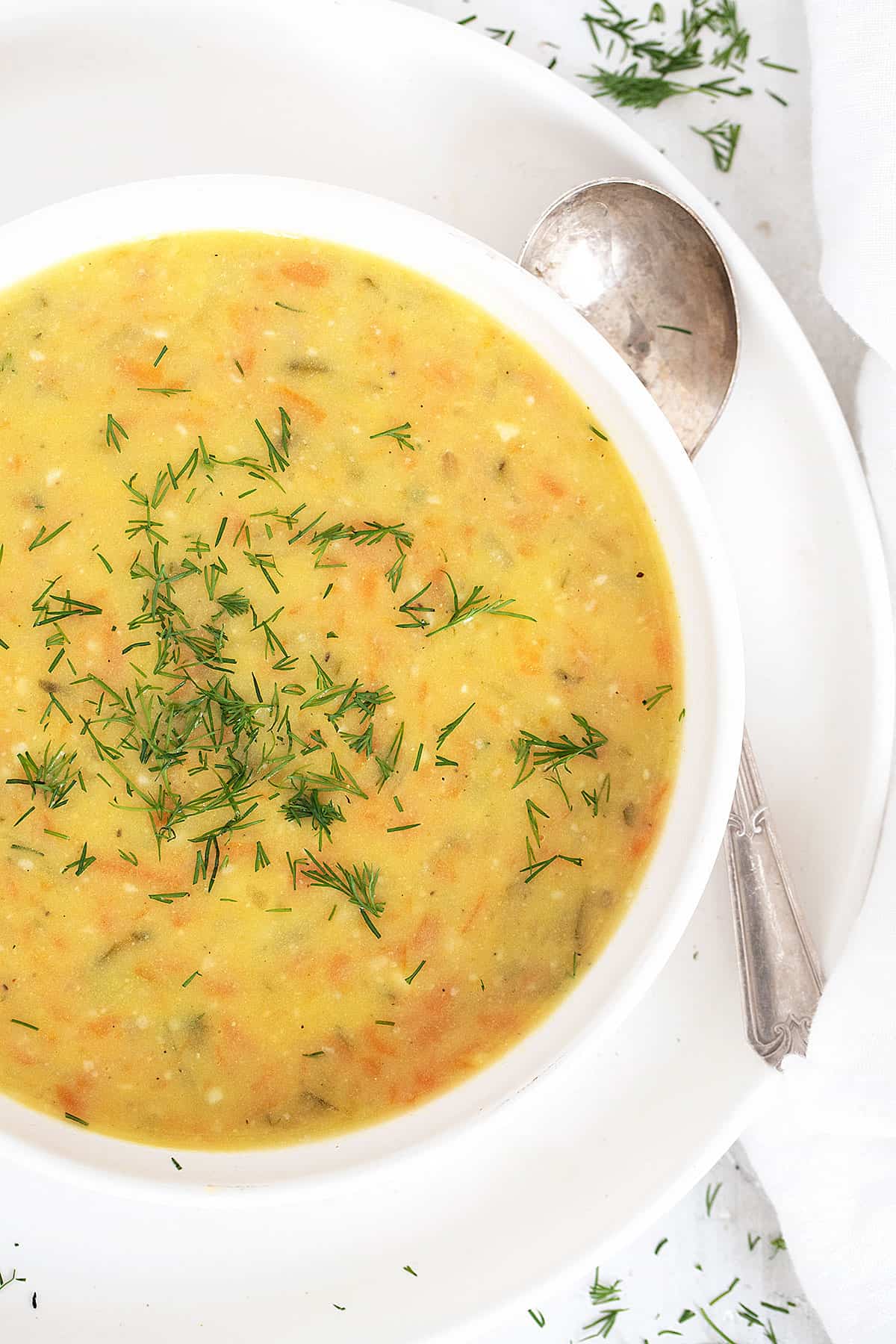 Polish potato and dill pickle soup in white bowl with spoon