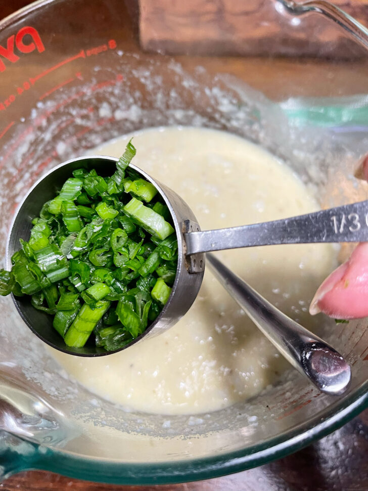 Adding green onion to batter.