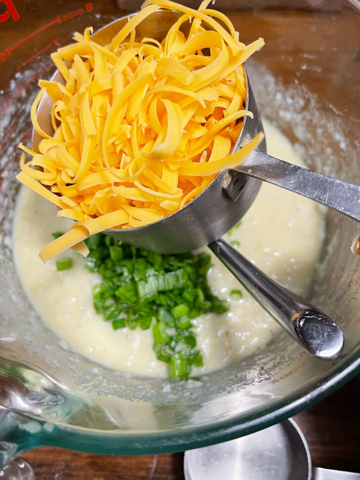 Adding shredded cheese to batter.