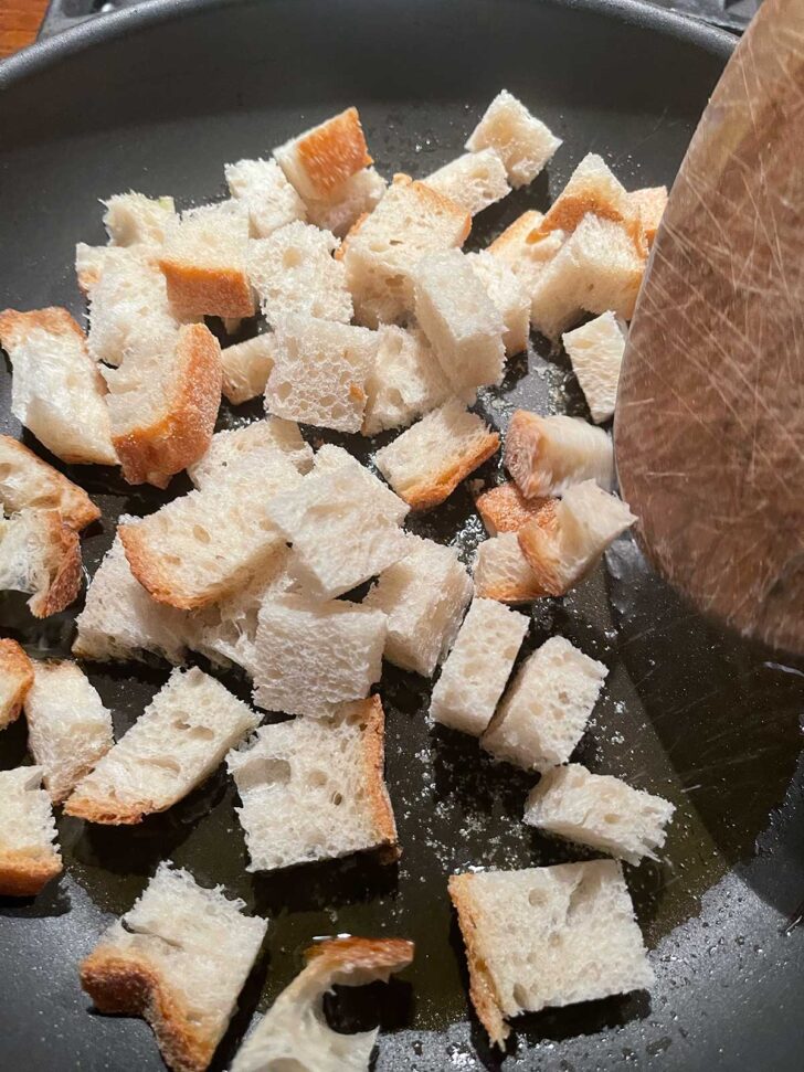 Browning bread cubes in a skillet.