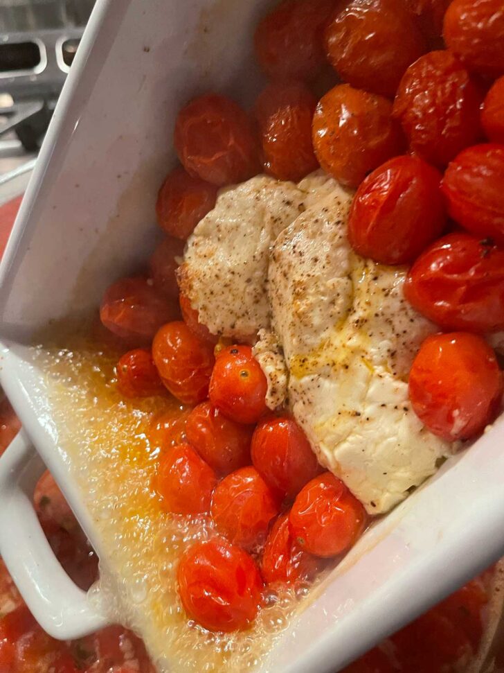 Adding cherry tomatoes and feta to the soup pot.
