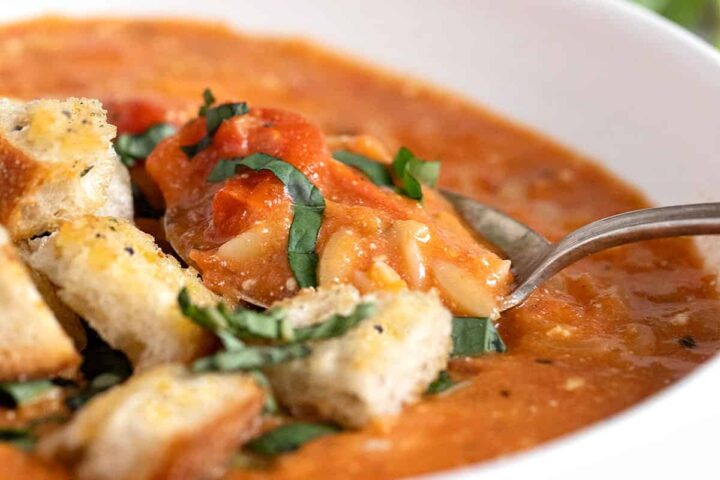 feta tomato orzo soup in white bowl with croutons