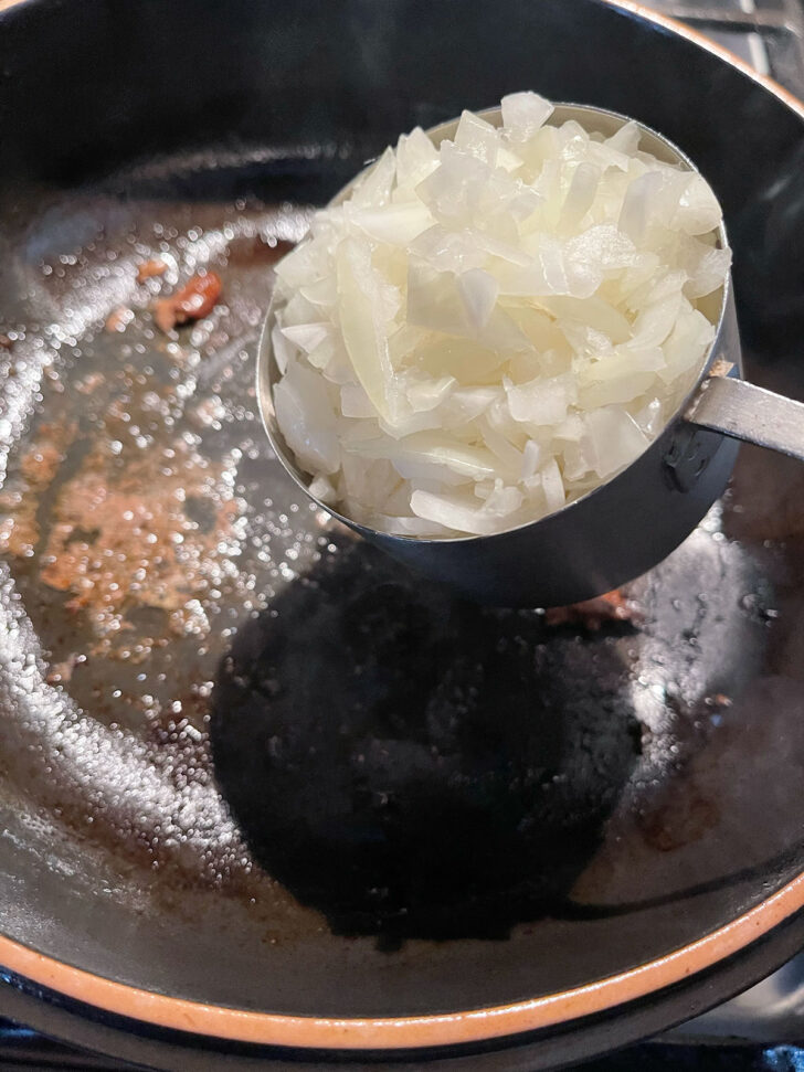 Adding onion to the skillet.