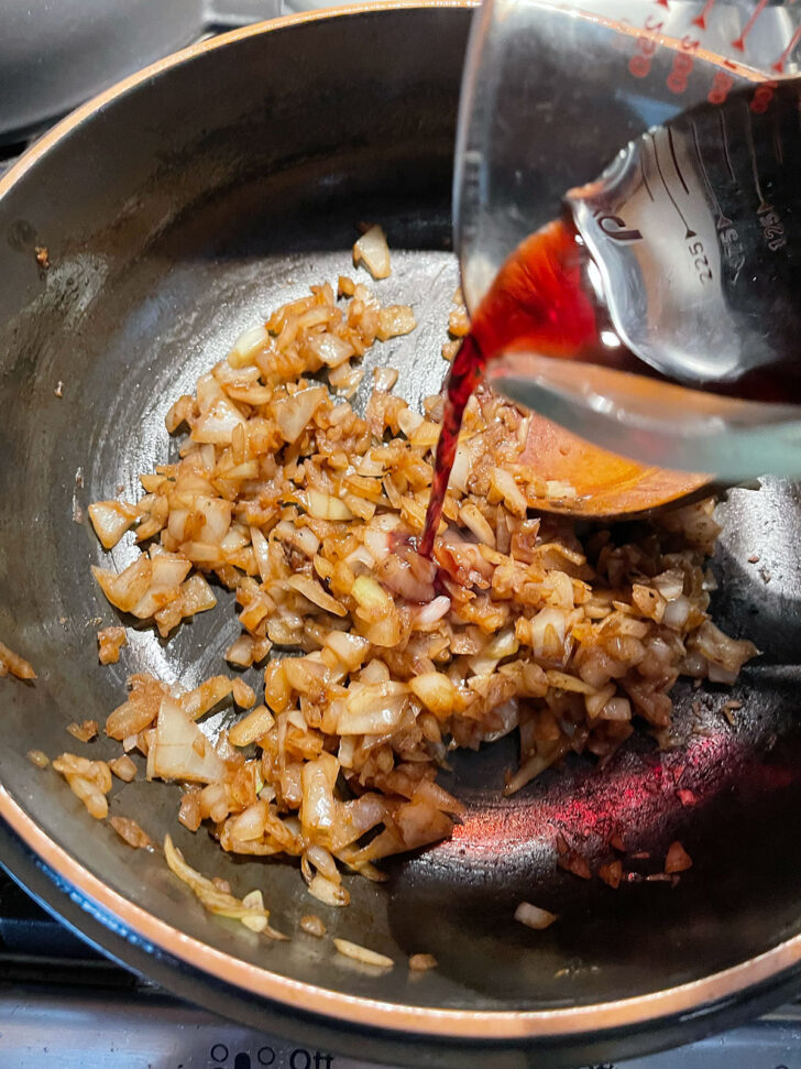 Adding the red wine to deglaze the pan.