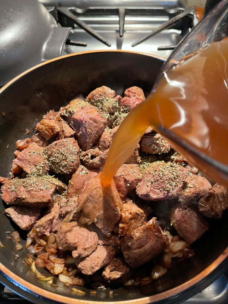 Adding beef broth to the pan.