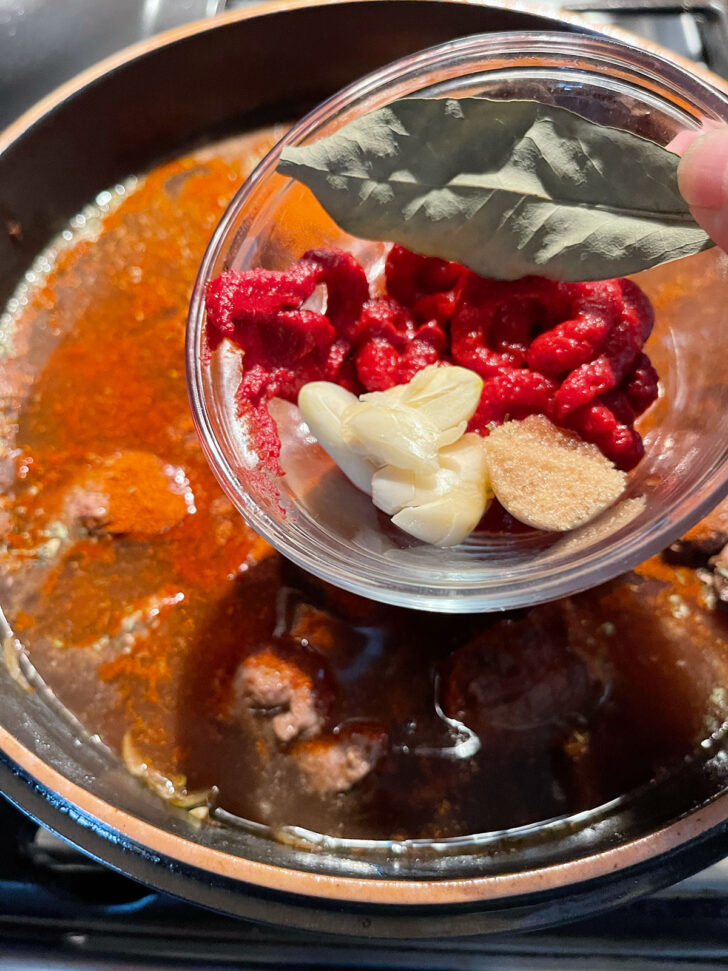 Adding the tomato paste, garlic, brown sugar and bay leaf to the pot.