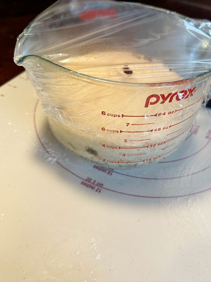 Dough set to rise in a measuring cup.