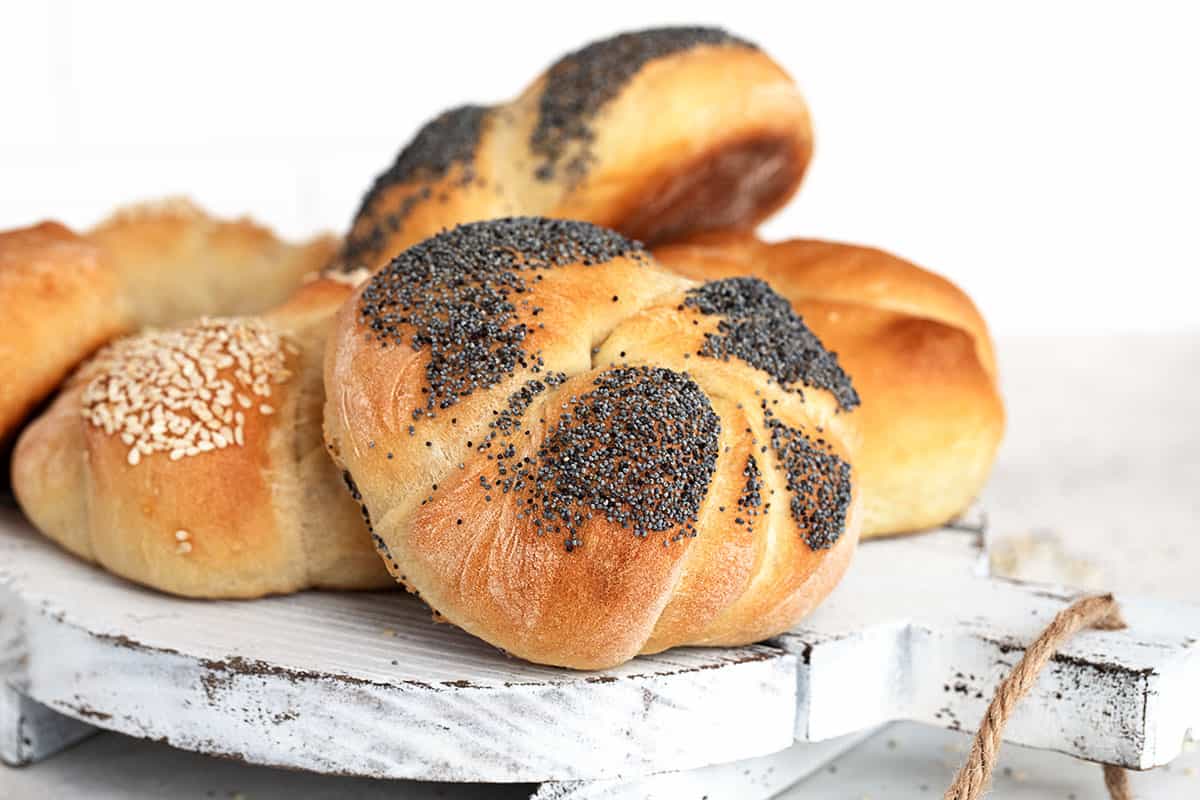 poppy seed, sesame seed and plain Kaiser rolls on white tray