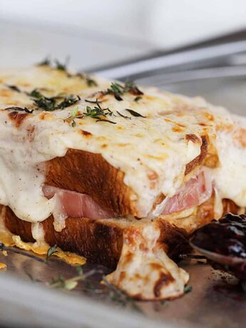 croque monsieur on baking sheet with raspberry jam on spoon