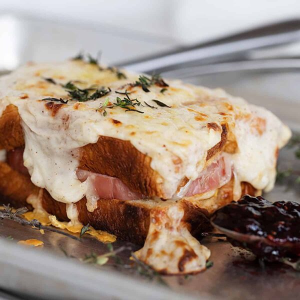 croque monsieur on baking sheet with raspberry jam on spoon