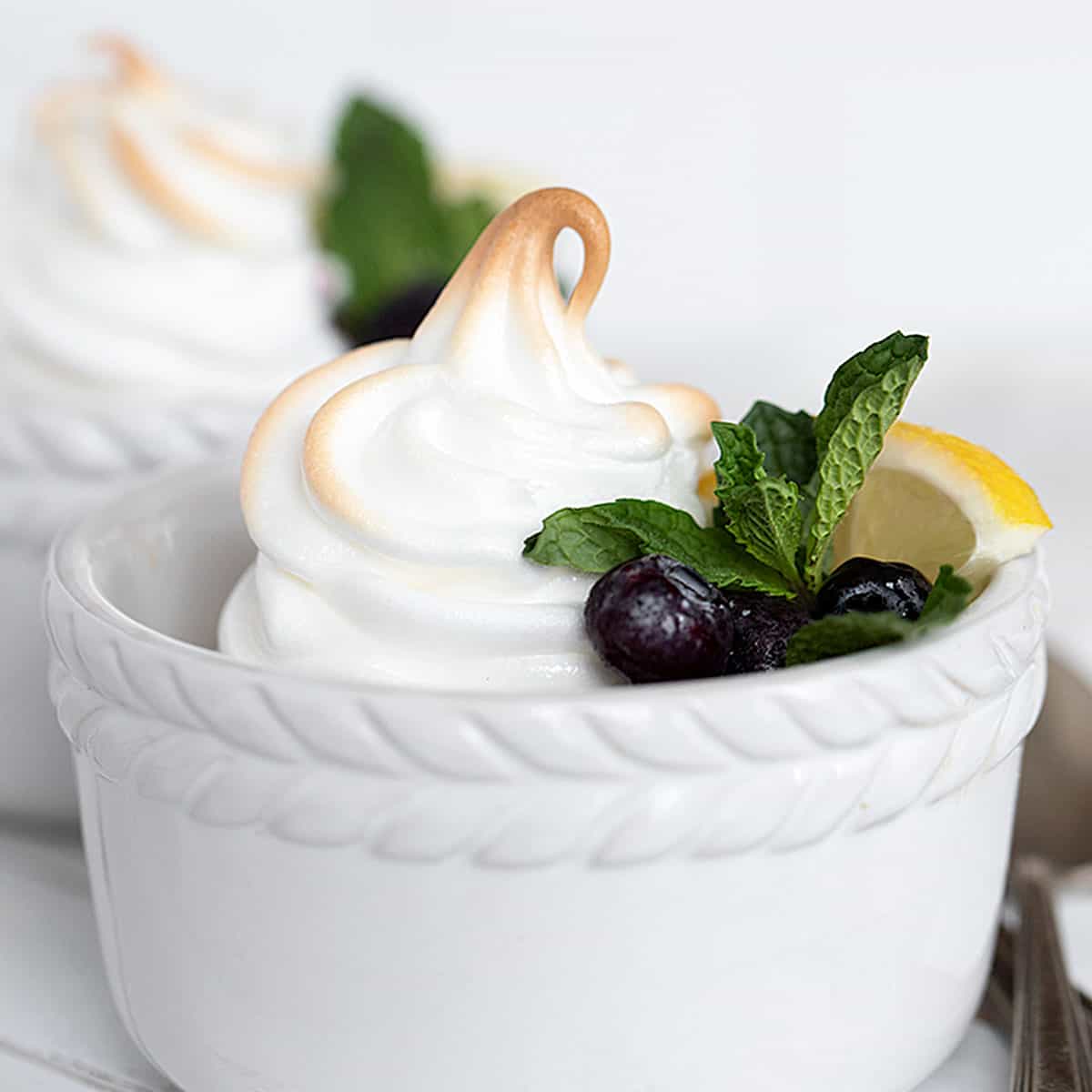 lemon meringue pudding in white ramekins with blueberries