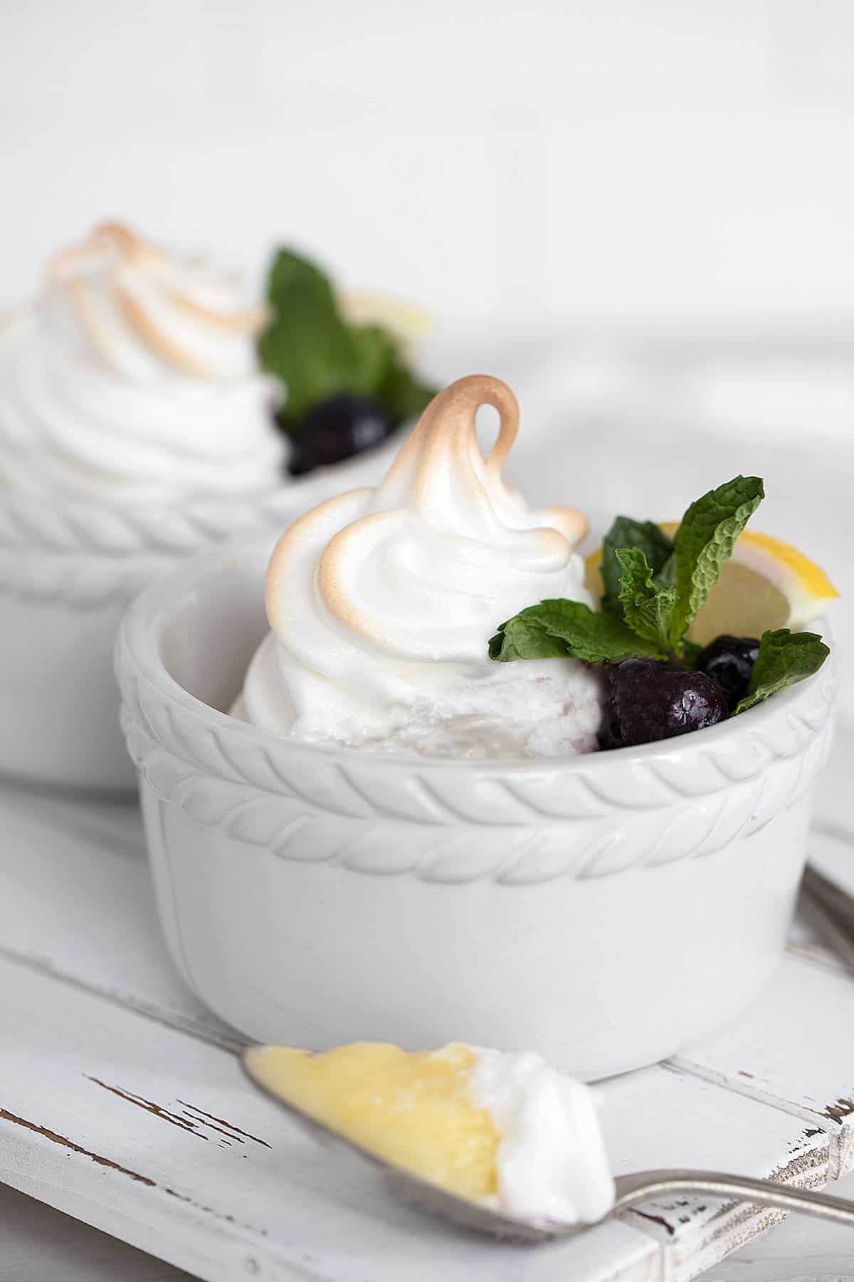 lemon meringue pudding in white ramekins with blueberries