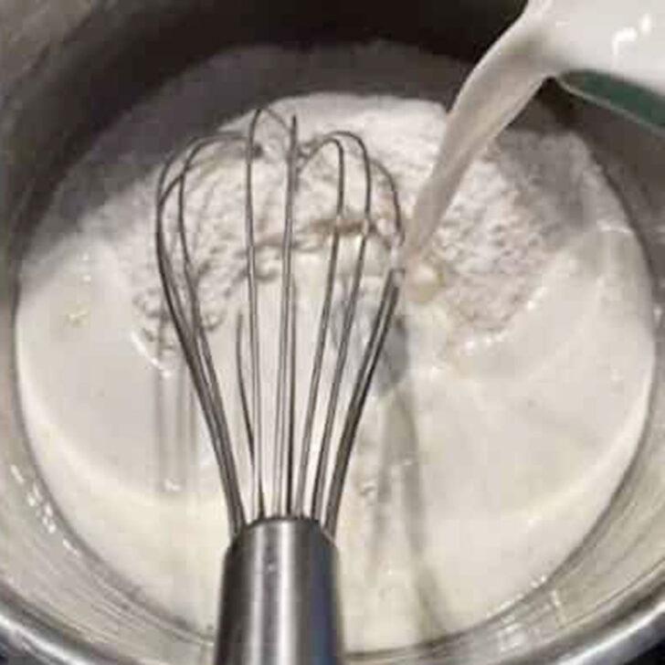 Adding milk to a saucepan with the lemon sugar.