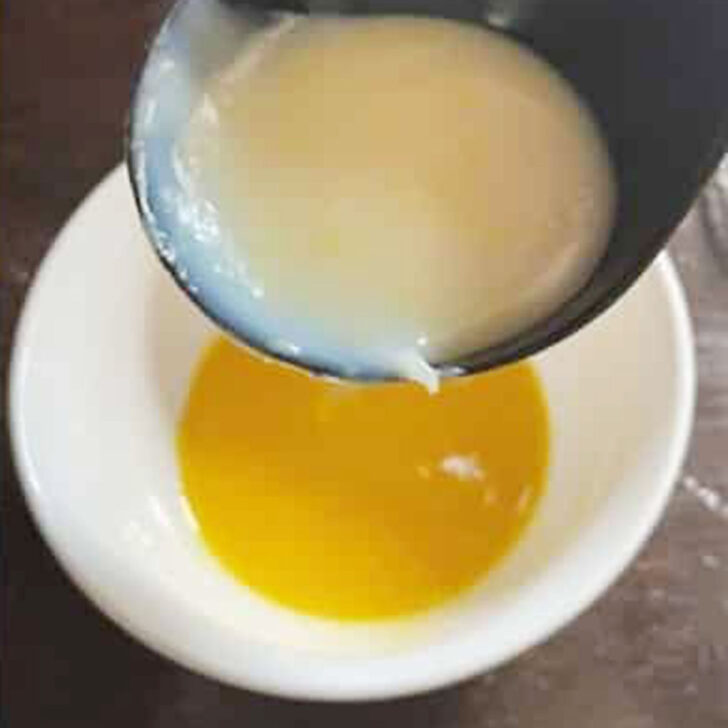 Adding some hot pudding to the eggs in a bowl.