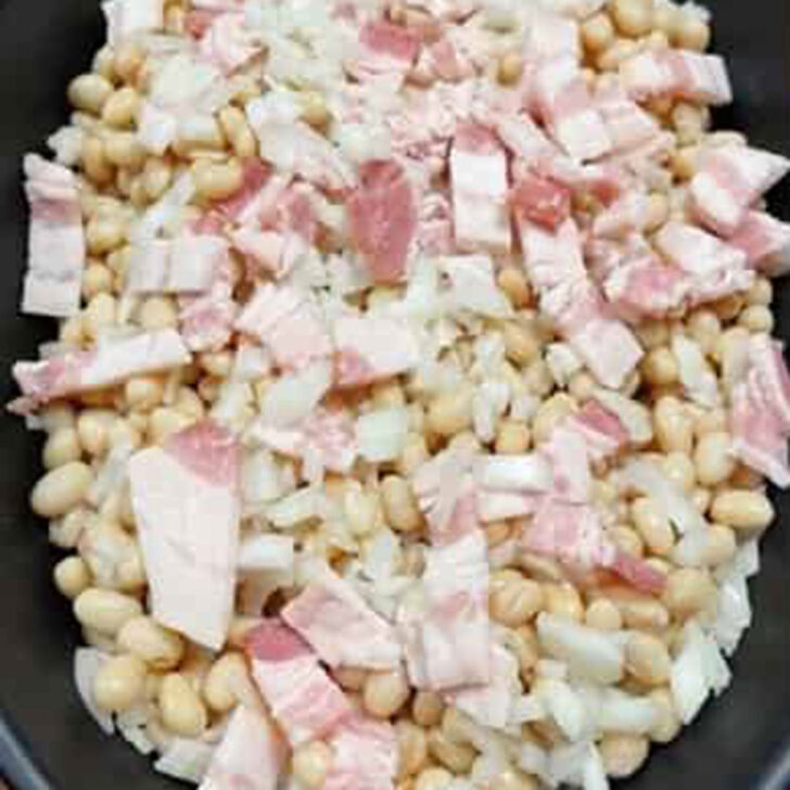 Drained, canned navy beans added to a casserole dish.