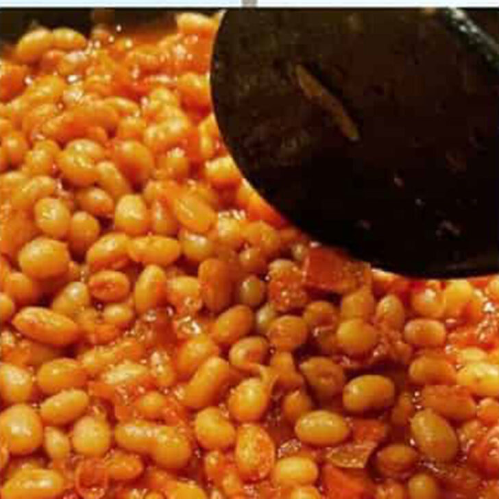 Stirring the baked beans and adding additional liquid to the baked beans.
