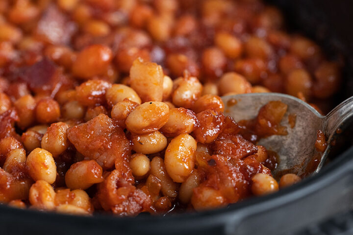 sweet sassy baked beans in baking dish with spoon