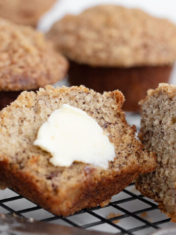 Banana crumb muffins on cooling rack split with butter.