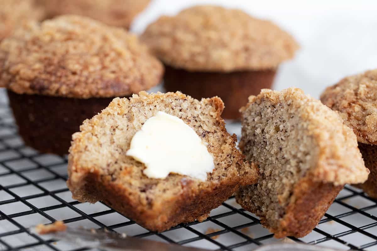 banana crumb muffins on cooling rack split with butter
