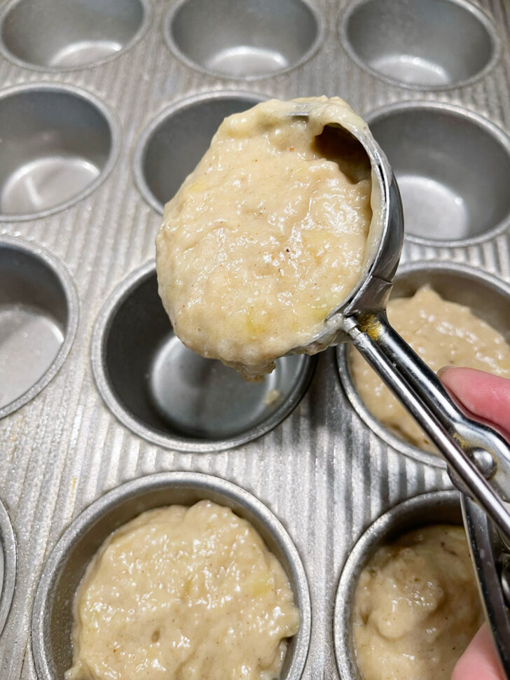 Using a scoop to put the batter in the muffin cups.