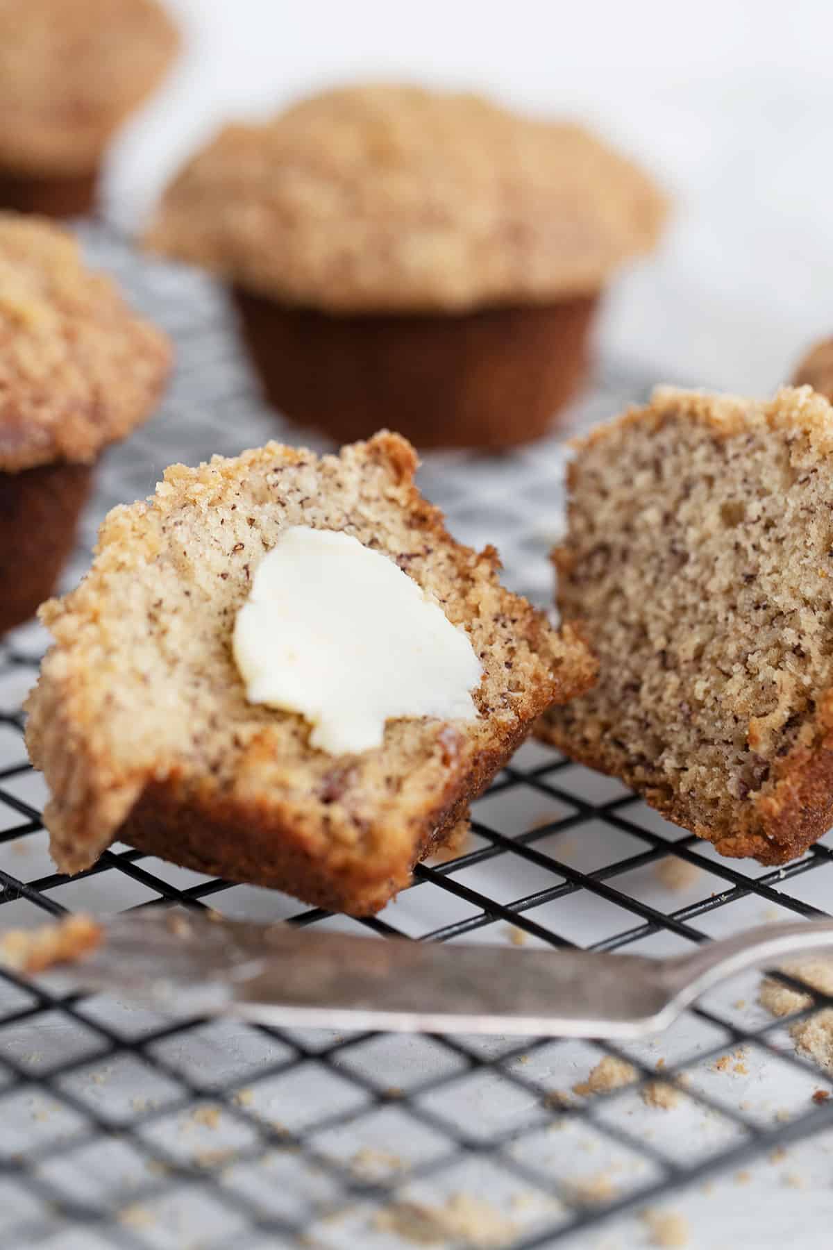 banana crumb muffins on cooling rack split with butter