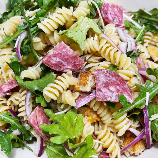Pasta salad with salami in a bowl.