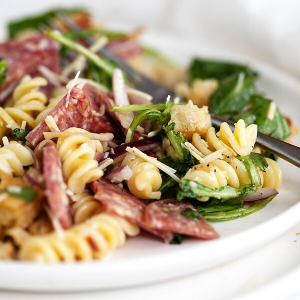 pasta salad with salami on plate with fork