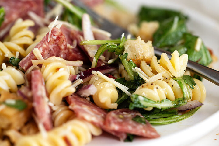 pasta salad with salami on plate with fork