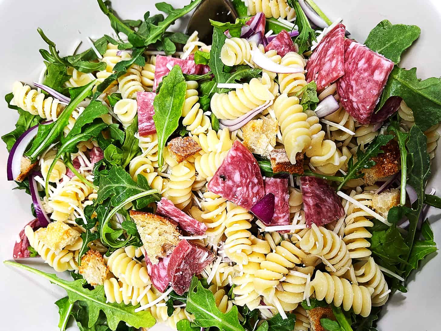 Pasta salad with salami in a bowl.