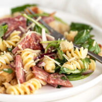 salami pasta salad on white plate with fork