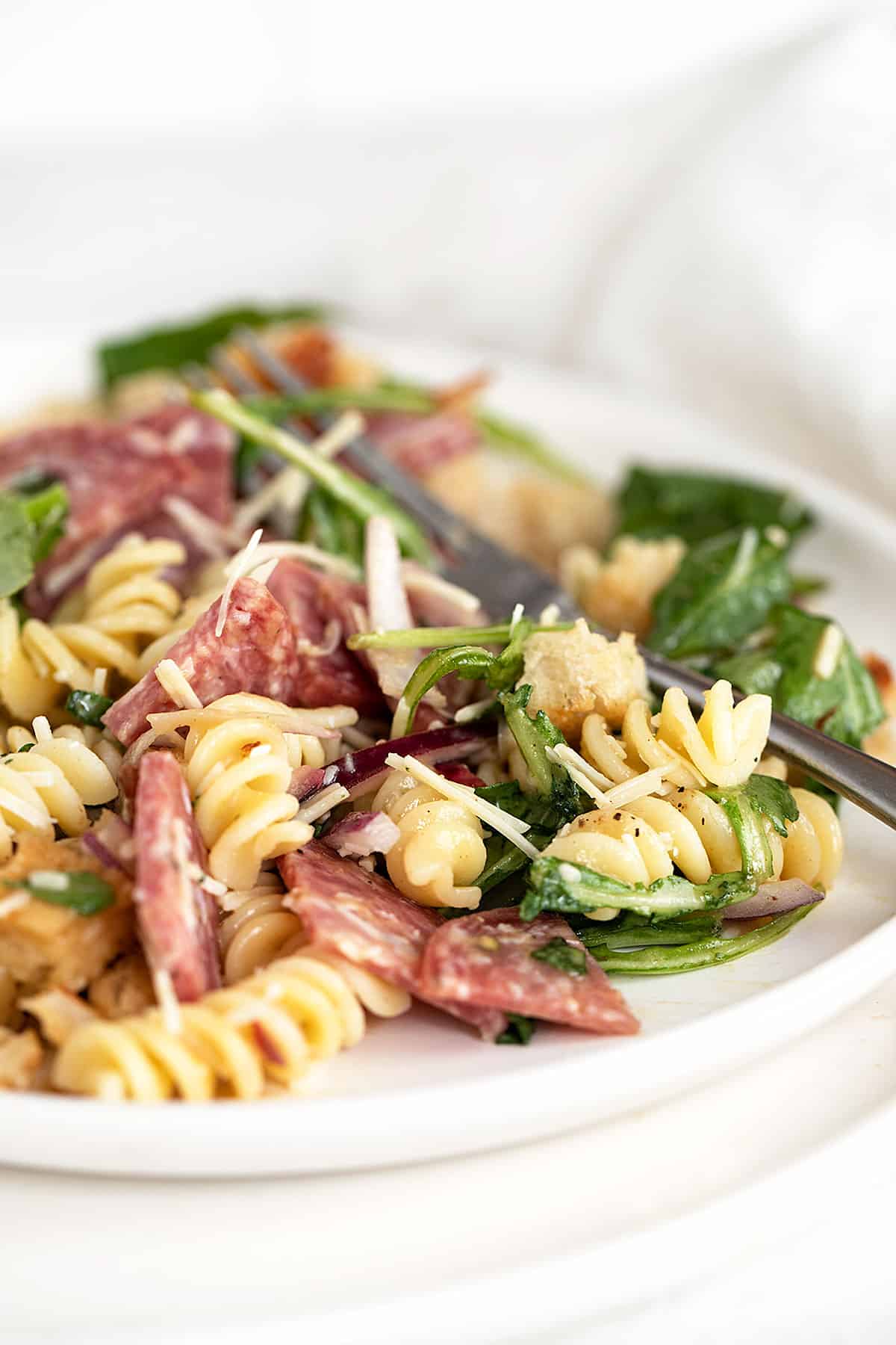 salami pasta salad on white plate with fork